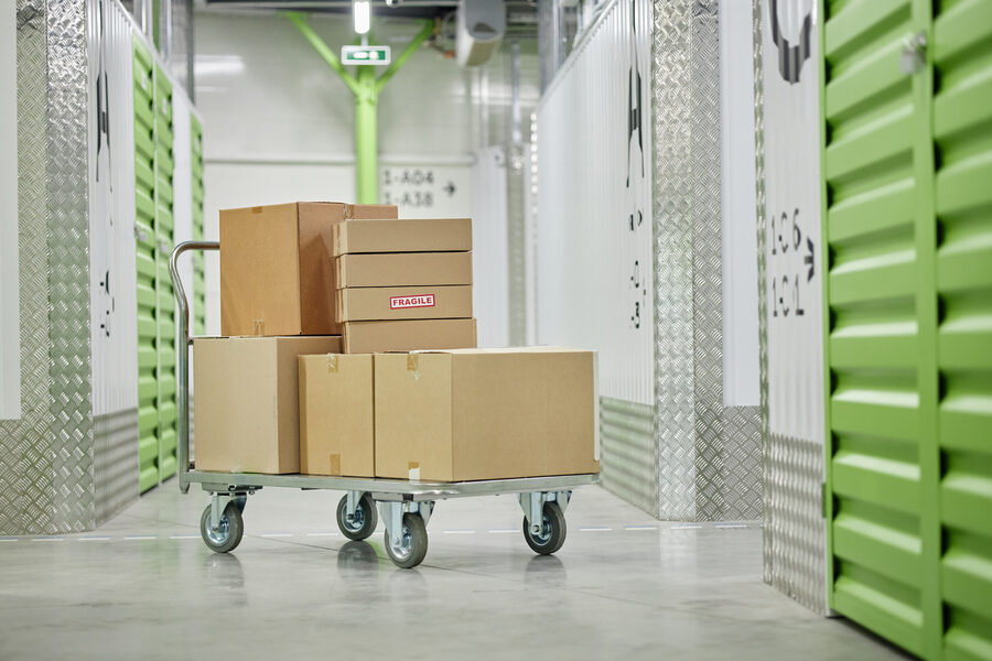 Stacked Cardboard Boxes on Trolley Standing in Self Storage Facility Corridor